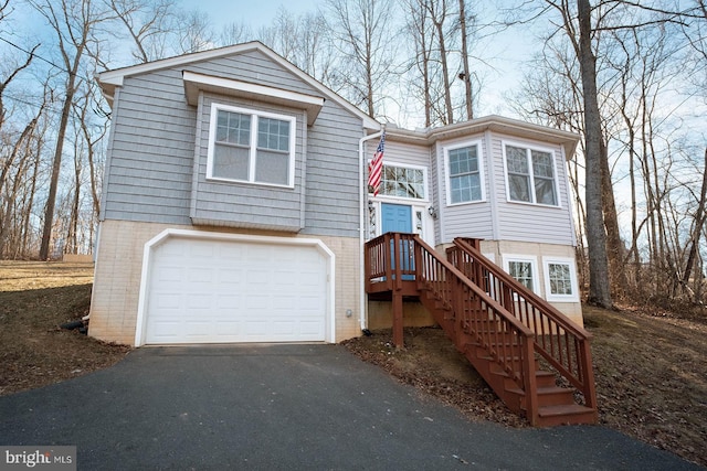 split foyer home featuring a garage, brick siding, and driveway