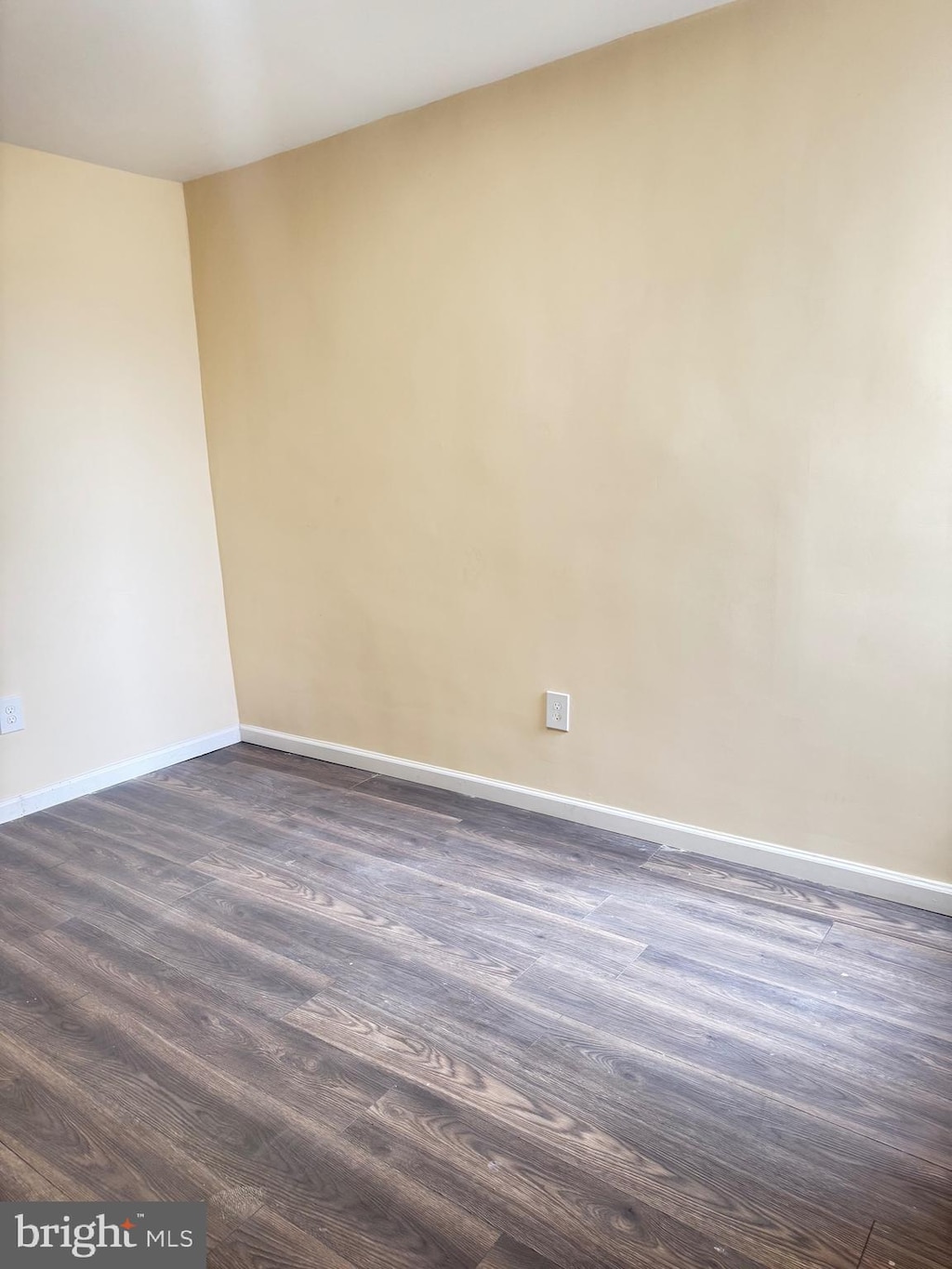 spare room with baseboards and dark wood-style floors