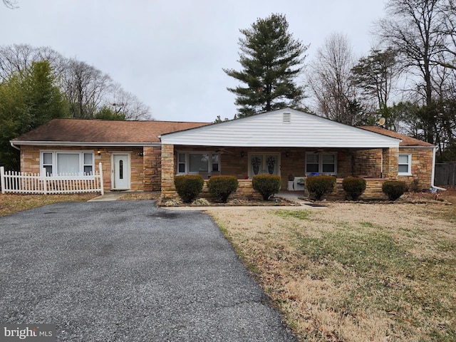 single story home featuring stone siding, covered porch, driveway, and fence