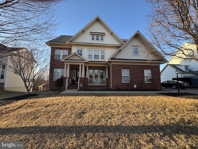 craftsman inspired home featuring a front lawn, a porch, and brick siding