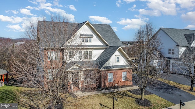 shingle-style home with brick siding and a front yard