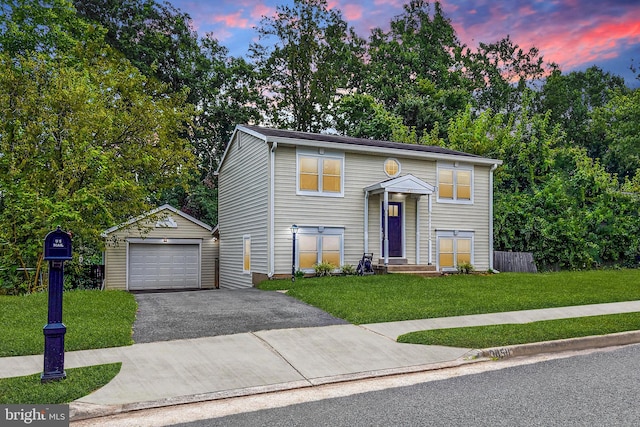 raised ranch with driveway, a lawn, a detached garage, fence, and an outdoor structure