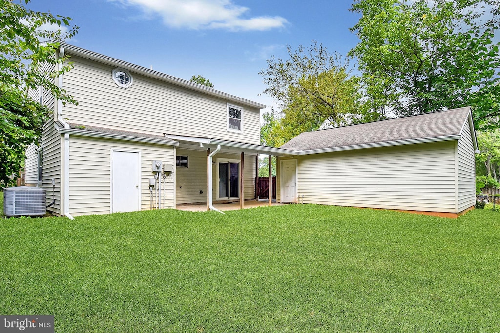 rear view of house featuring central AC, a lawn, and a patio area