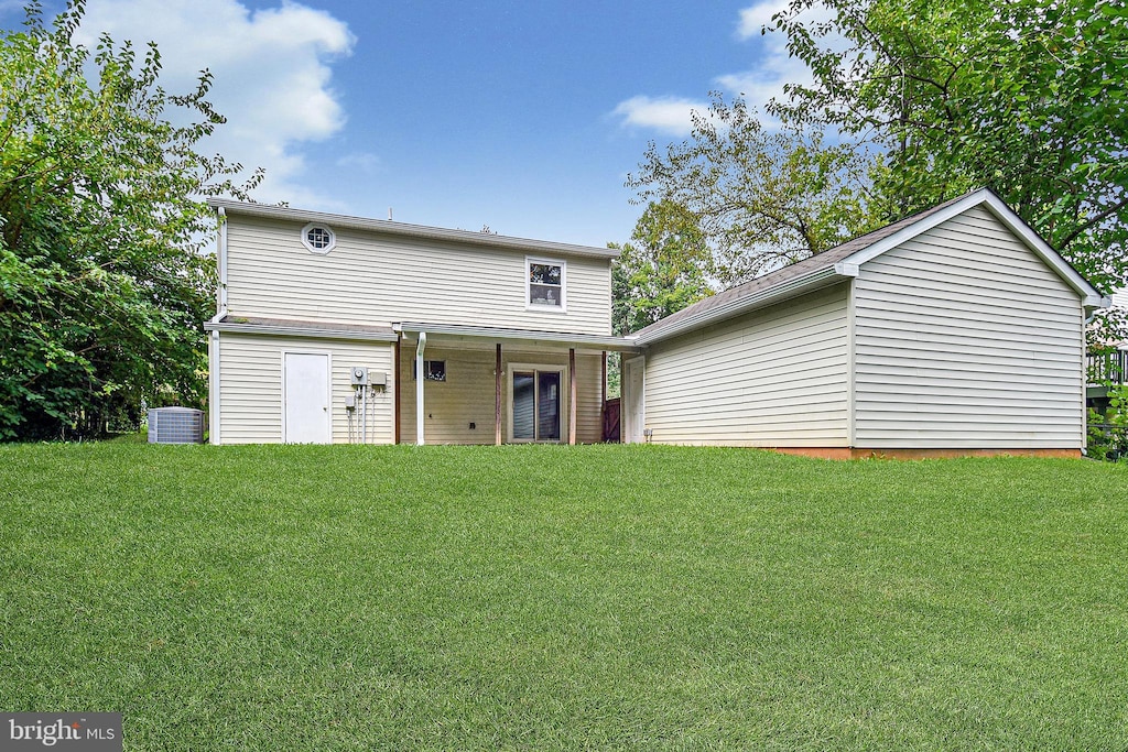 back of house with cooling unit and a yard