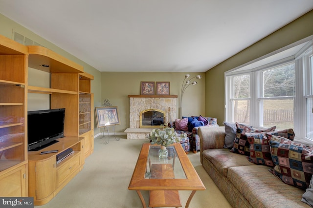 living room featuring a stone fireplace, baseboards, and light carpet