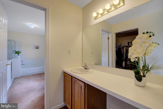 full bathroom with vanity, a spacious closet, and a washtub