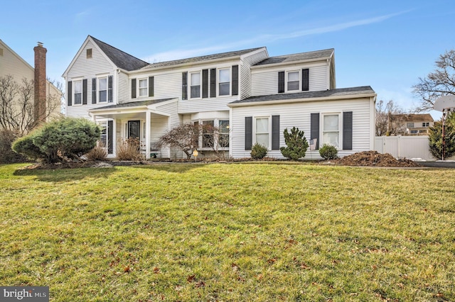 traditional-style home featuring a front lawn and fence