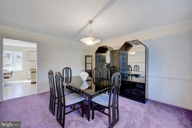 carpeted dining area featuring crown molding and baseboards