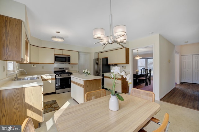 kitchen with a sink, a kitchen island, stainless steel appliances, light countertops, and a healthy amount of sunlight