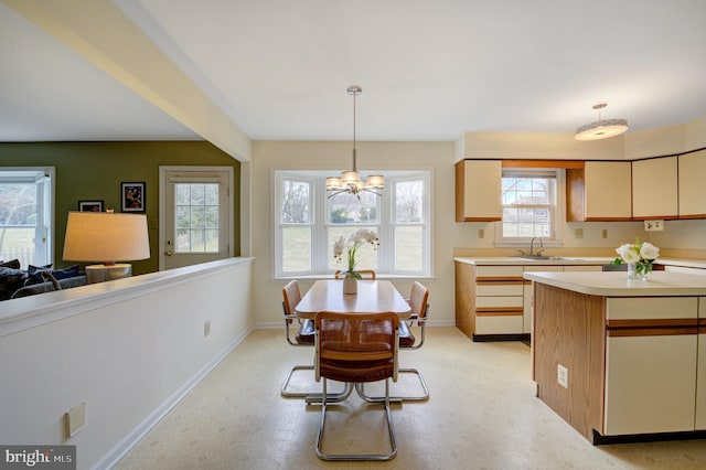 dining room featuring a chandelier, light floors, and baseboards