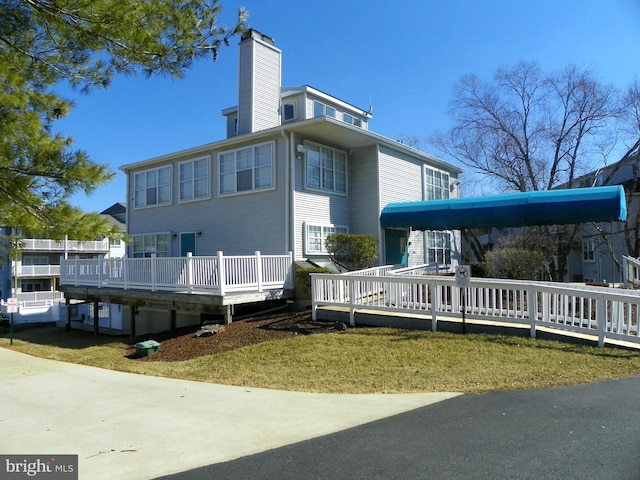 back of property with a chimney and a wooden deck