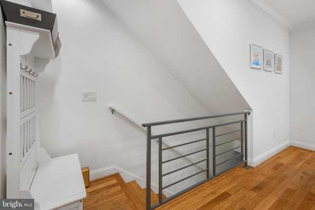 stairway with crown molding, baseboards, and wood finished floors