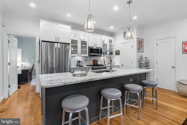 kitchen with ornamental molding, a sink, white cabinets, appliances with stainless steel finishes, and backsplash