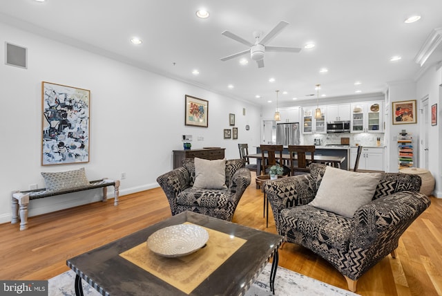 living room with recessed lighting, baseboards, light wood-style flooring, and crown molding