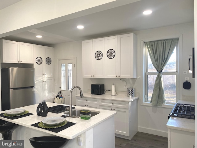 kitchen with freestanding refrigerator, white cabinetry, and a sink