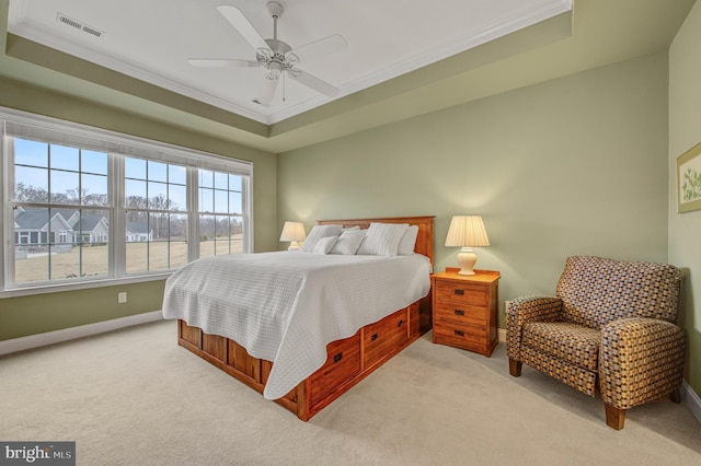 bedroom with light carpet, visible vents, a tray ceiling, and ornamental molding