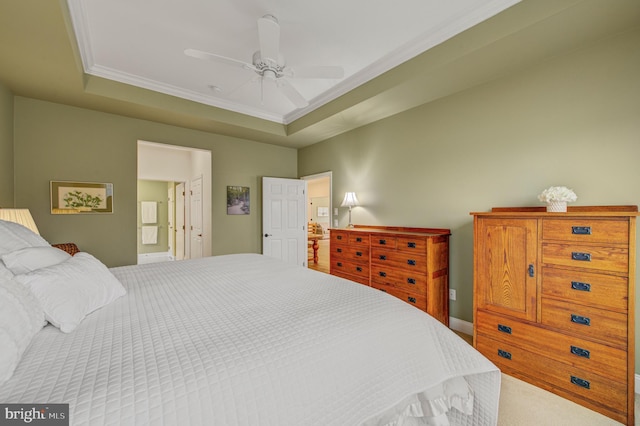 bedroom featuring a ceiling fan, ensuite bath, carpet flooring, crown molding, and a raised ceiling