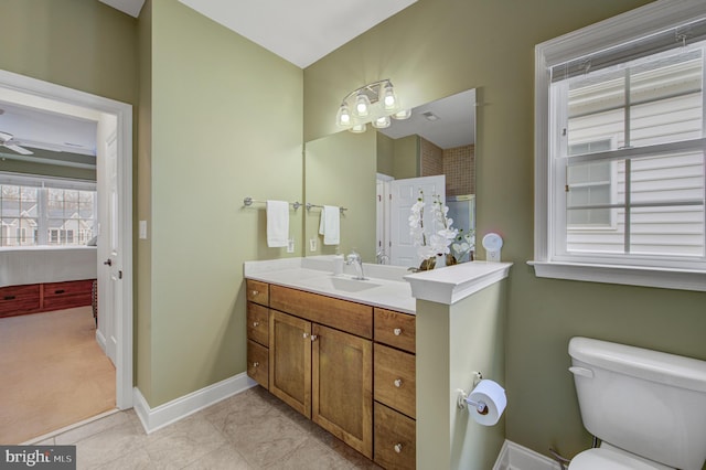 bathroom with vanity, toilet, a ceiling fan, and baseboards