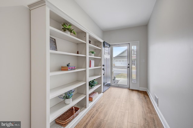 entryway with baseboards, visible vents, and light wood finished floors