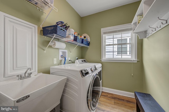 clothes washing area with wood finished floors, baseboards, laundry area, a sink, and washer and dryer