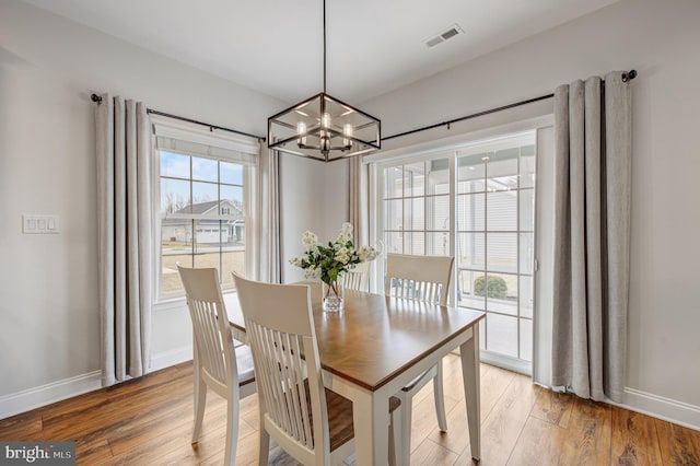 dining room featuring a notable chandelier, light wood-style flooring, visible vents, and baseboards