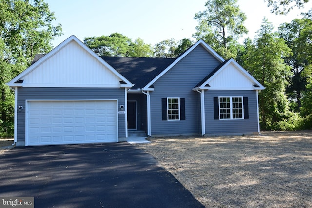 ranch-style house featuring an attached garage and aphalt driveway