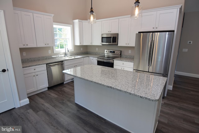 kitchen with appliances with stainless steel finishes, a center island, white cabinetry, and a sink