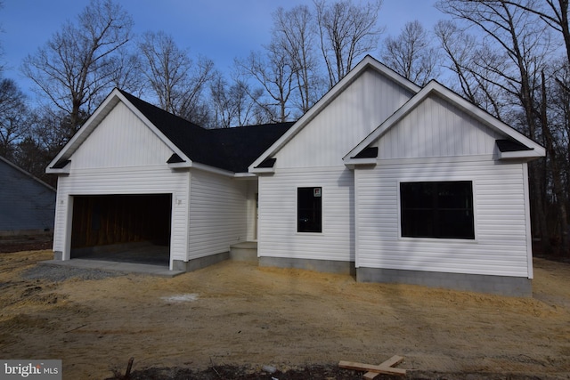 modern farmhouse with an attached garage, driveway, and board and batten siding