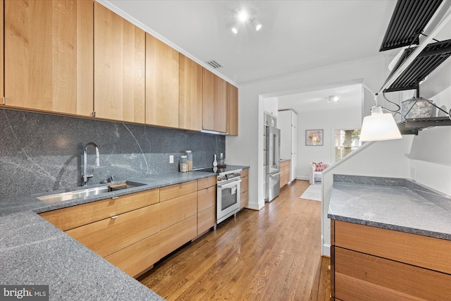 kitchen with electric range oven, backsplash, wood finished floors, light brown cabinetry, and a sink