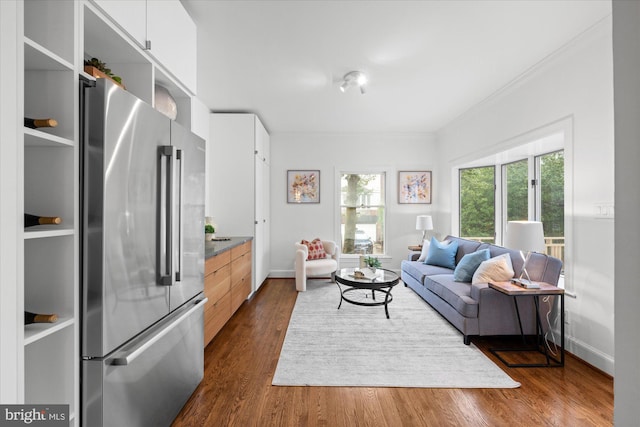 living area with crown molding, dark wood finished floors, and baseboards