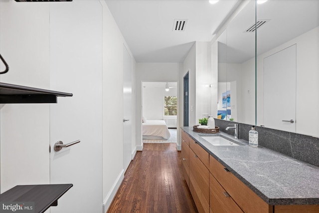 bathroom with visible vents, vanity, ensuite bath, and wood finished floors