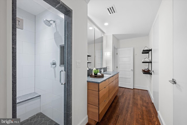 full bath with a stall shower, baseboards, visible vents, wood finished floors, and vanity