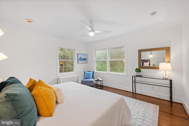 bedroom with ornamental molding, a ceiling fan, baseboards, and wood finished floors