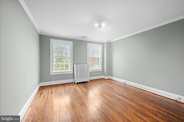 empty room with baseboards, radiator heating unit, visible vents, and hardwood / wood-style floors