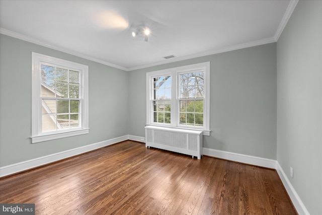 spare room with visible vents, baseboards, ornamental molding, radiator, and dark wood finished floors