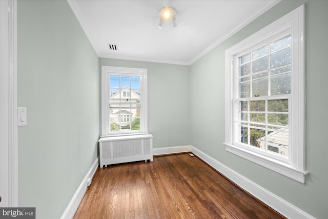 spare room with radiator heating unit, baseboards, dark wood-type flooring, and ornamental molding