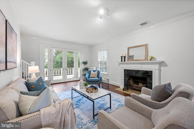 living room with ornamental molding, a fireplace, wood finished floors, and visible vents