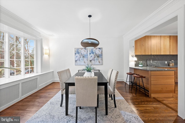 dining room with baseboards, ornamental molding, and dark wood finished floors