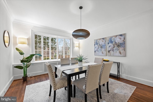 dining space featuring baseboards, wood finished floors, and crown molding