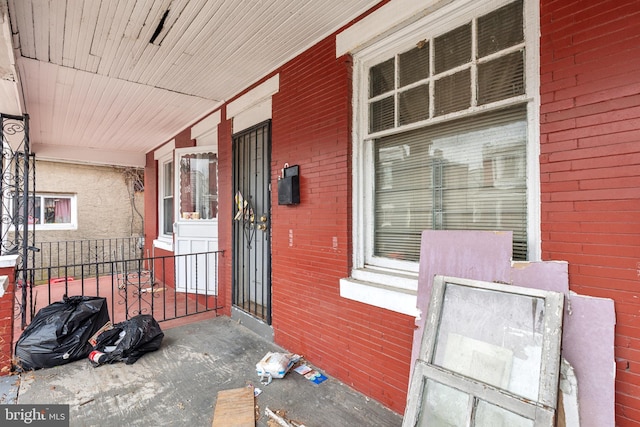 entrance to property featuring a porch and brick siding