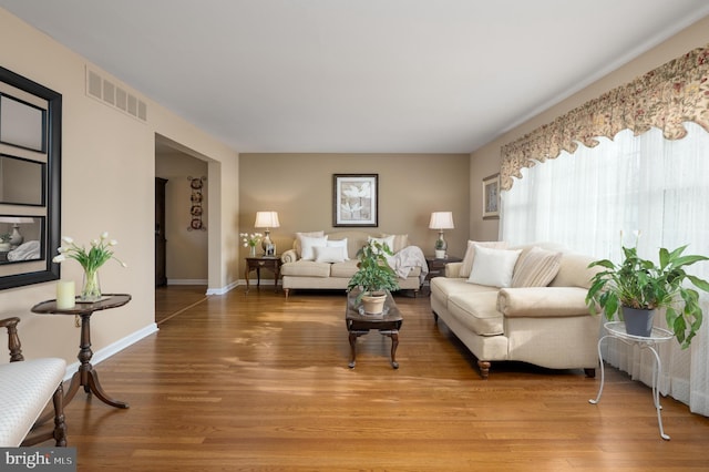 living room with light wood-style flooring, baseboards, and visible vents