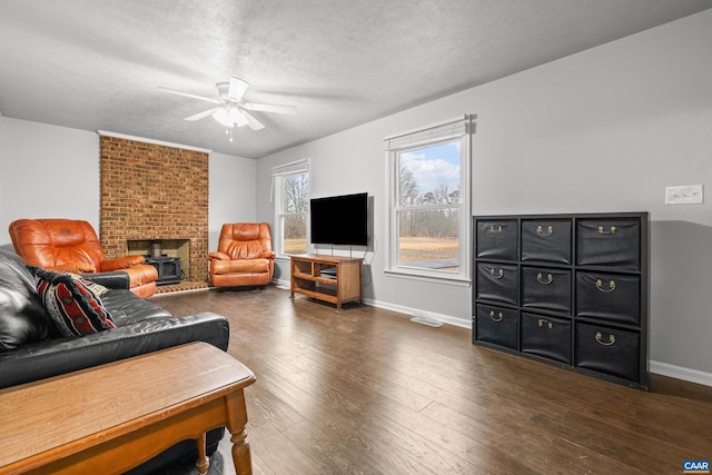 living room with wood finished floors, visible vents, baseboards, ceiling fan, and a textured ceiling