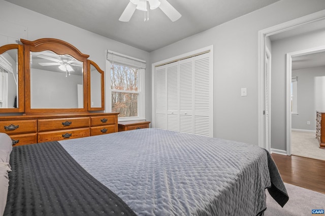 bedroom with carpet, wood finished floors, a ceiling fan, baseboards, and a closet