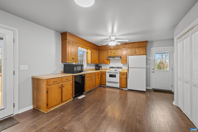 kitchen with under cabinet range hood, black appliances, light countertops, and dark wood-type flooring