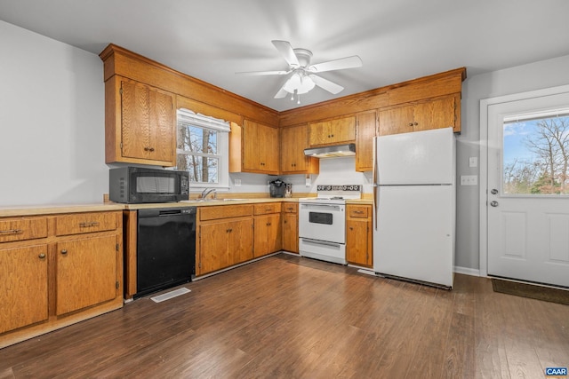 kitchen with dark wood-type flooring, light countertops, a wealth of natural light, black appliances, and a sink