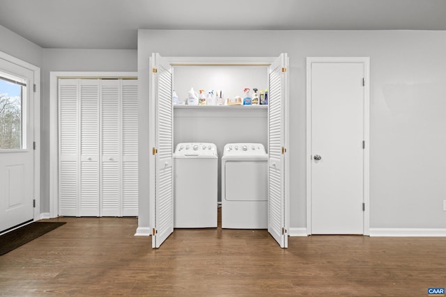 laundry area with laundry area, washing machine and dryer, baseboards, and wood finished floors