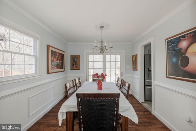 dining area featuring a chandelier, wainscoting, crown molding, and dark wood finished floors