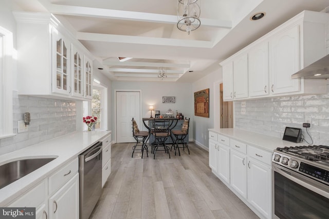 kitchen featuring an inviting chandelier, appliances with stainless steel finishes, glass insert cabinets, light wood-style floors, and white cabinetry