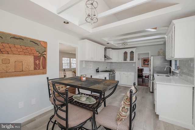 dining area featuring baseboards, light wood-type flooring, a raised ceiling, and an inviting chandelier