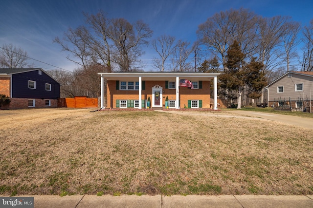 bi-level home featuring a front yard, brick siding, and fence